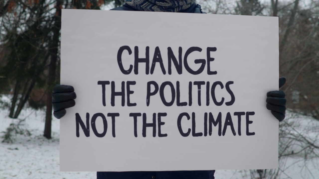 一名参加罢工的活动人士举着“改变政治而不是气候”的牌子视频素材
