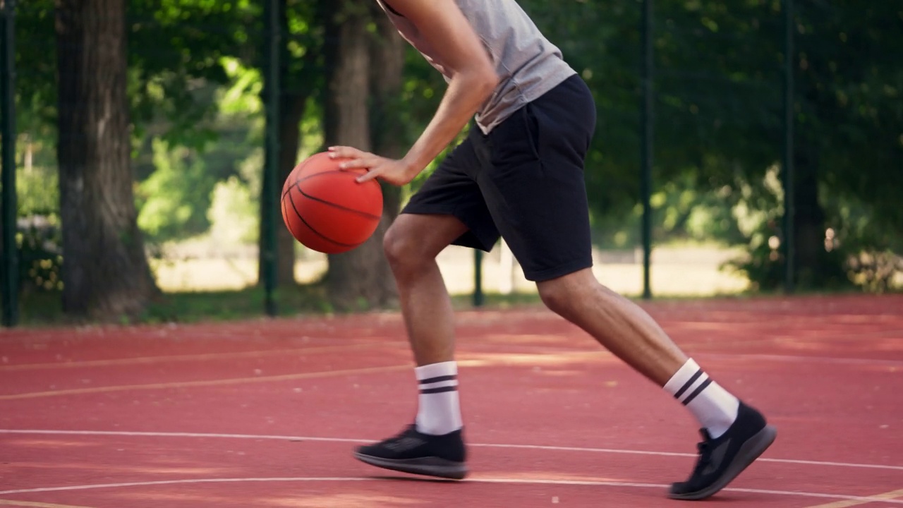 活跃的年轻男性打街头篮球，运球，在球场上训练视频下载