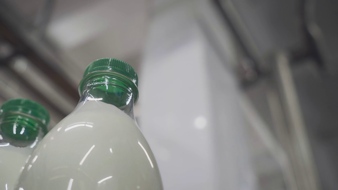 带有绿色瓶盖的牛奶瓶在移动。乳制品制造视频素材