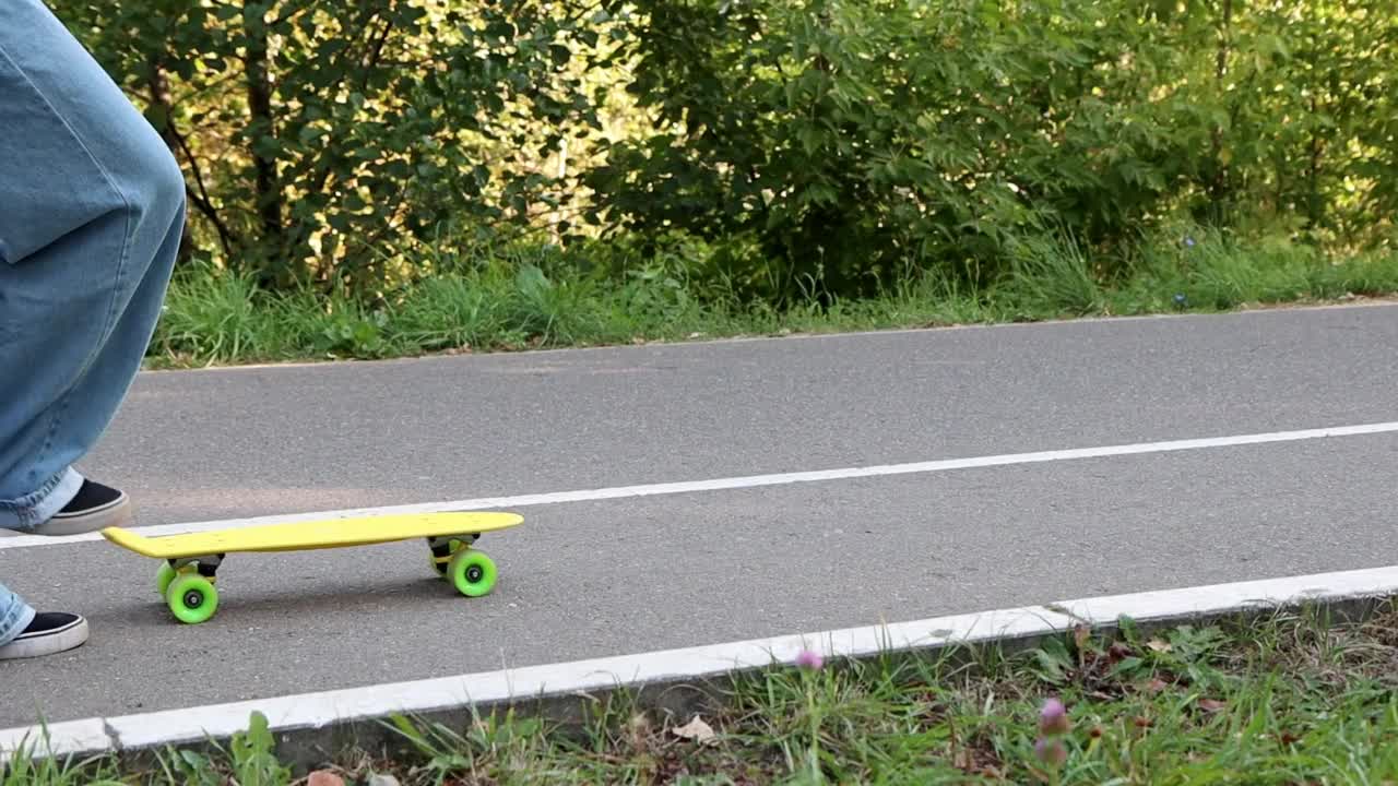 滑板——滑板者的脚推着一块黄色的滑板滚下马路视频素材