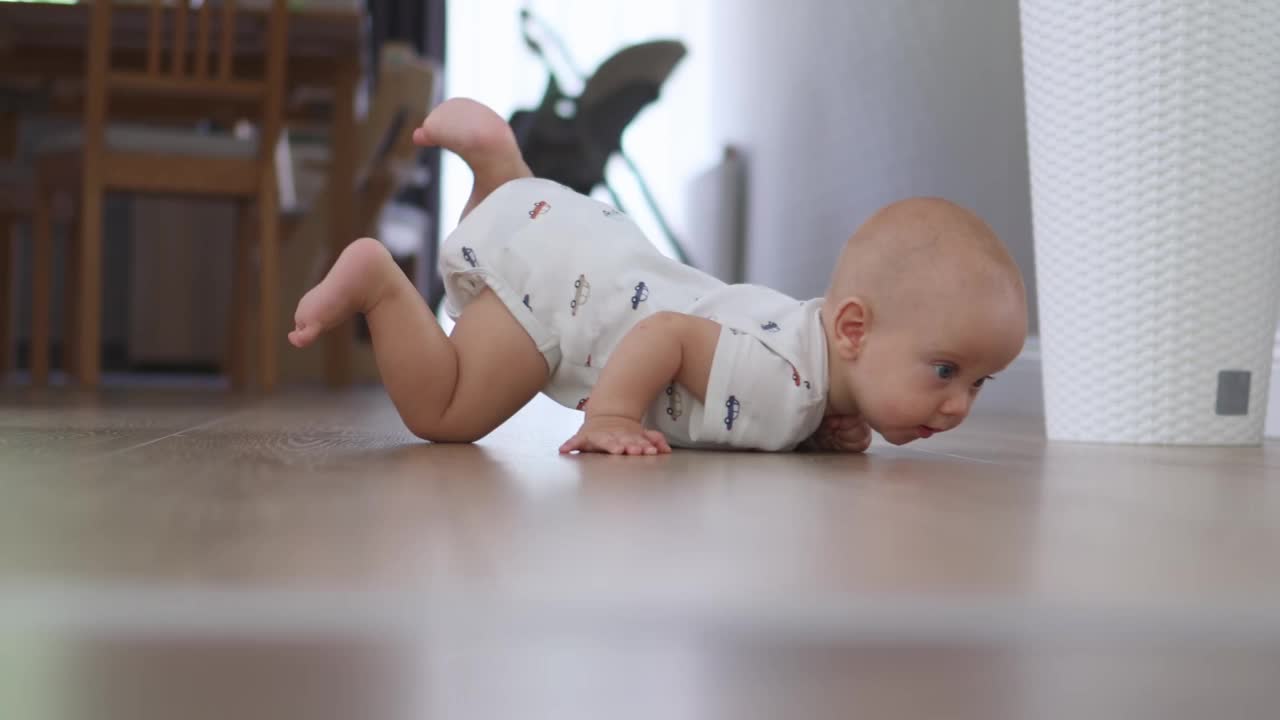 美丽的宝宝躺在地板上看着镜头，微笑着，表现出爬行的情绪视频下载