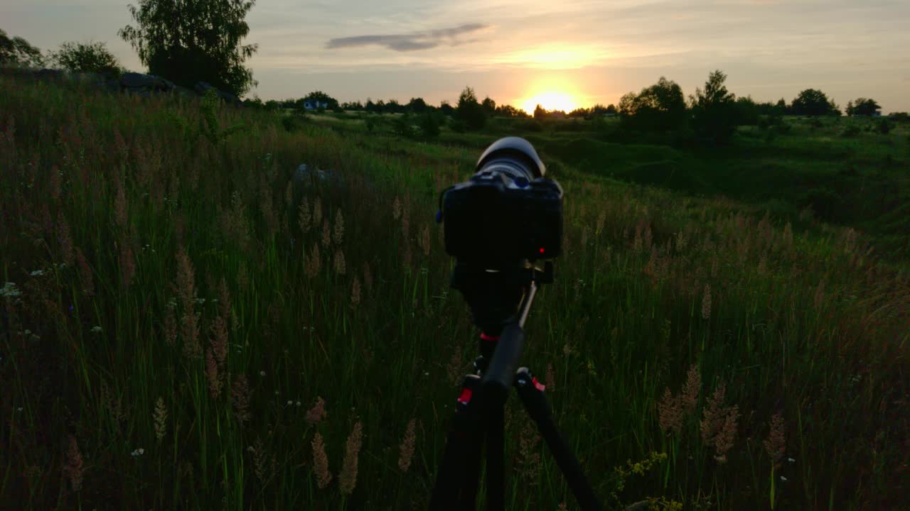 三脚架上的相机拍摄夏日草地上的日出视频素材