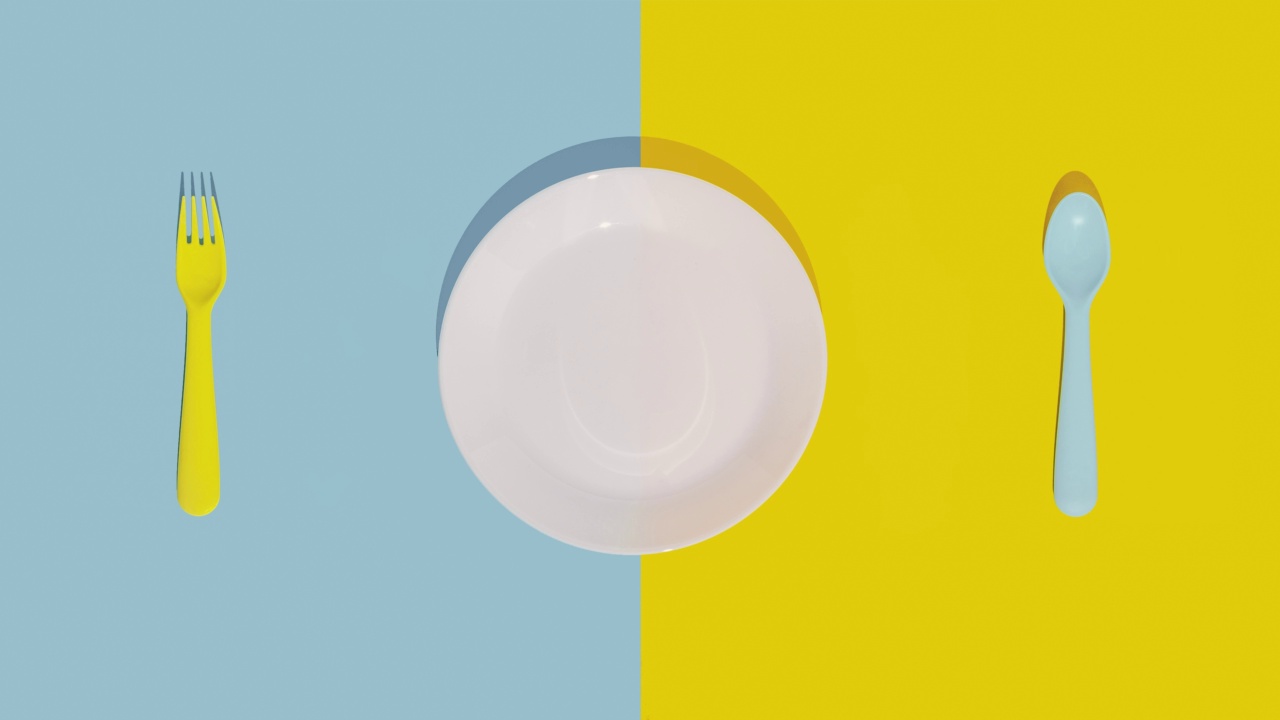 盘子和移动的勺子和叉子在柔和的蓝色和黄色背景平躺4k定格视频动画视频下载