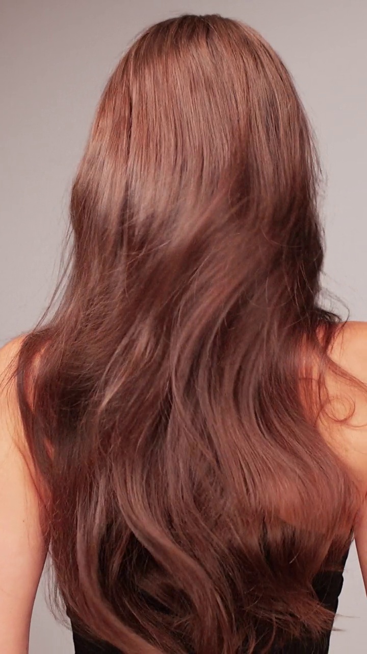 美丽，诱人的褐发女子显示头发的相机在白色背景。棕色、健康的头发闪闪发光、飘动视频下载