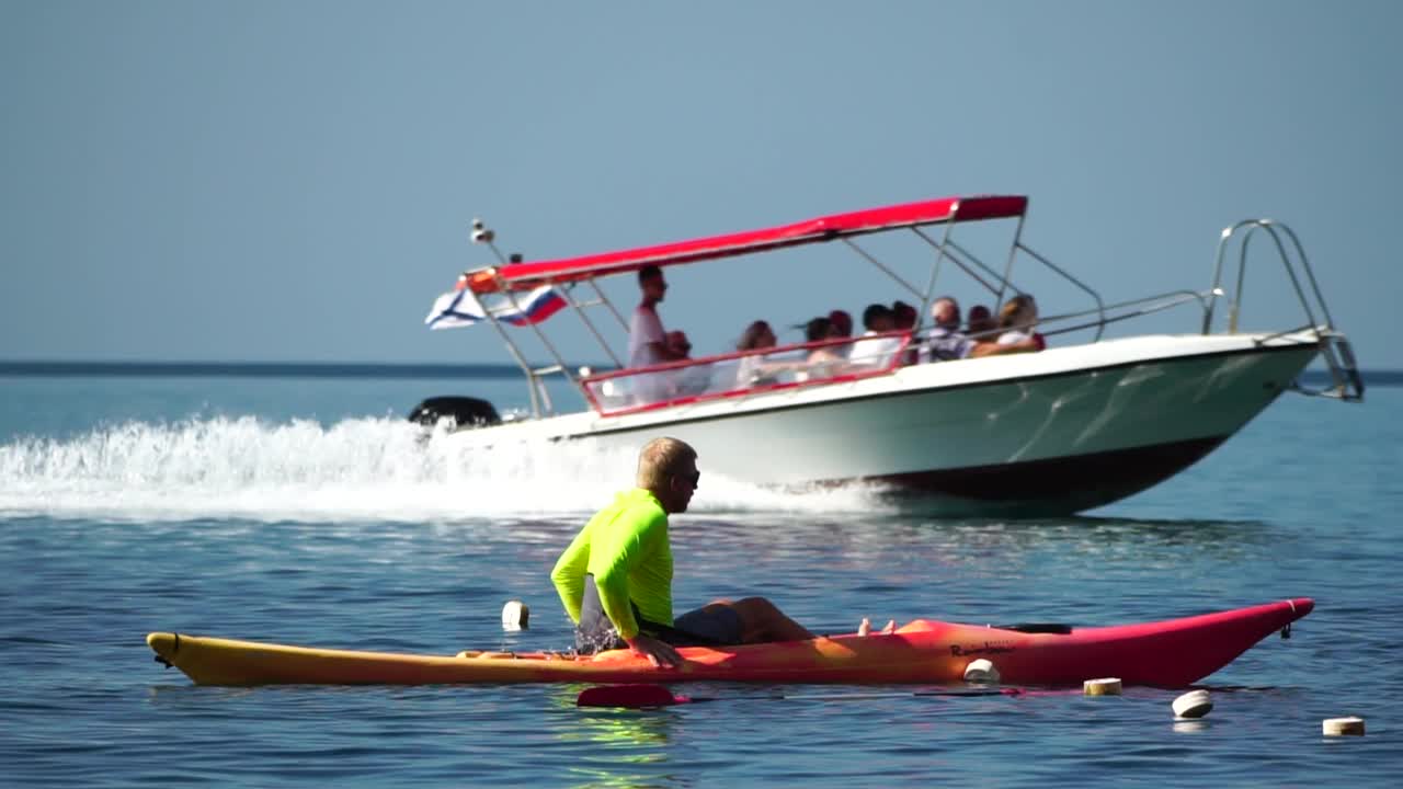 海人皮艇。运动员男子在夏日夕阳下划着皮艇在海里游泳。健康强壮的男性喜欢户外活动的生活方式和水上运动在假期。慢动作视频下载