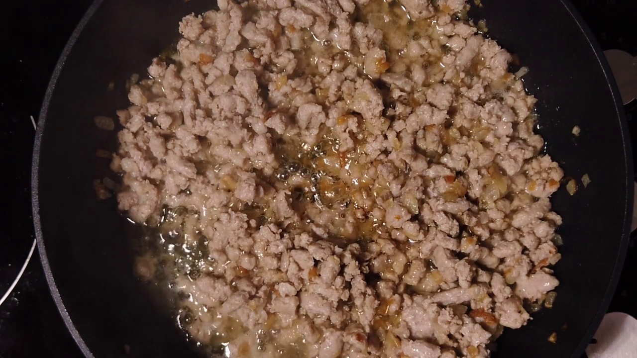 洋葱和肉末。厨师用玻璃盖子盖住锅。波伦亚的烹饪过程。视频下载