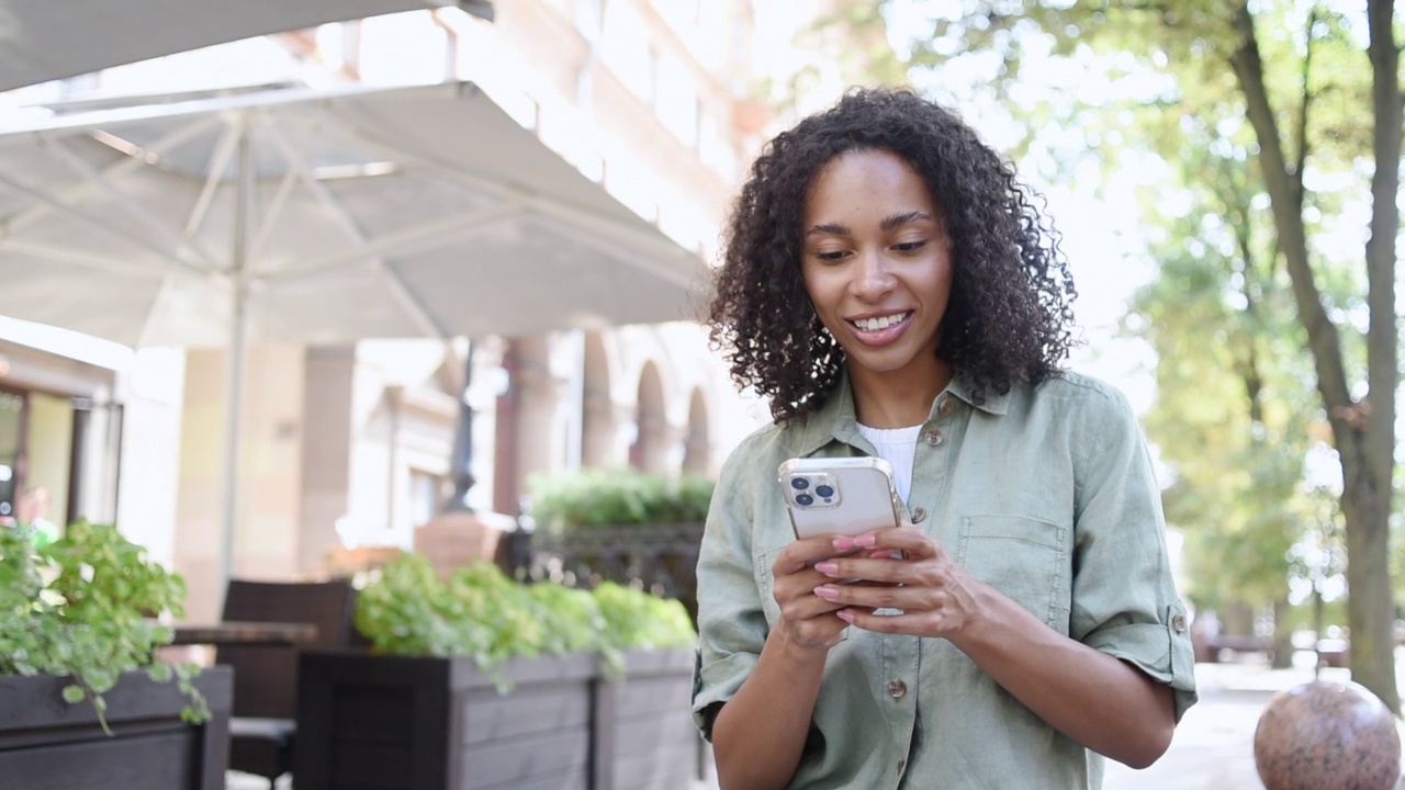 快乐的女人在城市里使用智能手机视频素材