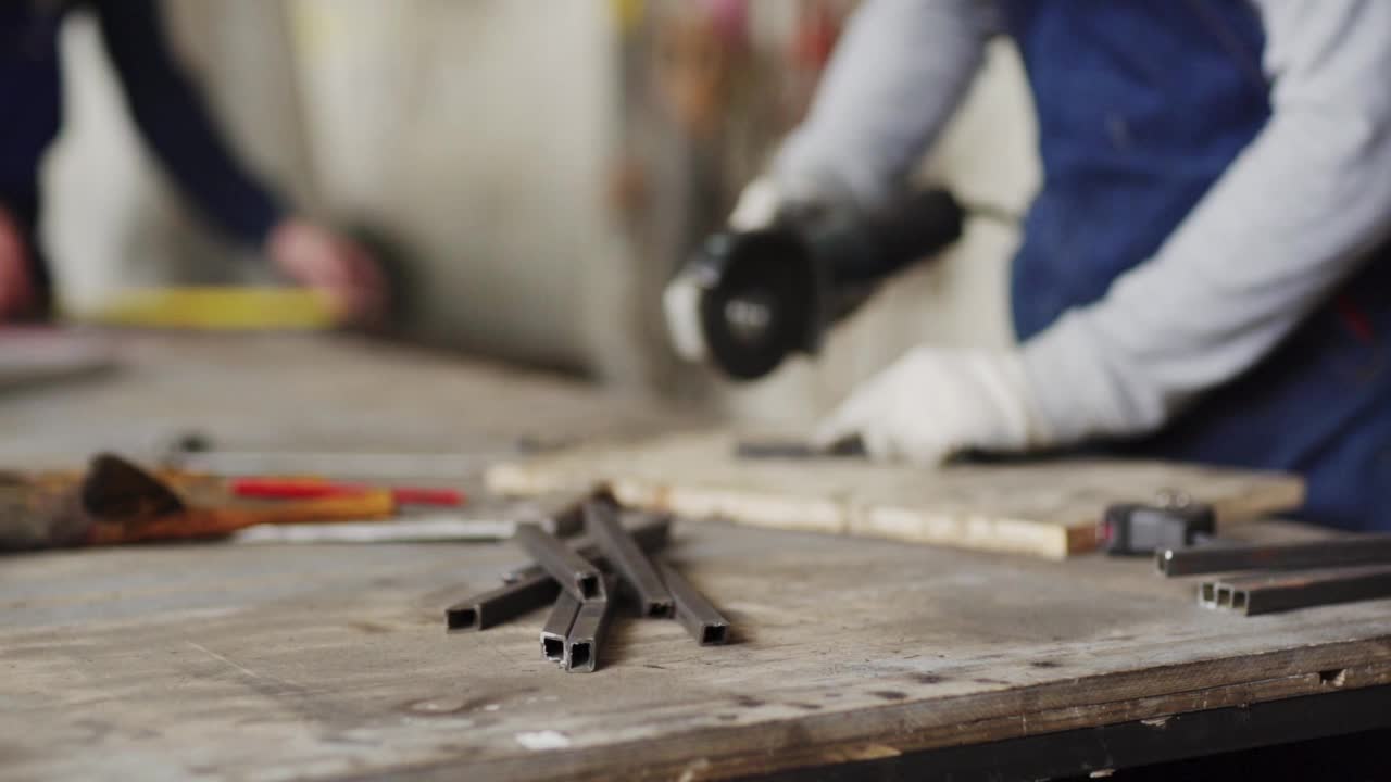 放大无法辨认的金属工人的手在保护手套切割金属板与角磨床站在工作台。在慢动作中，火花从切割盘飞离，侧视图特写视频下载