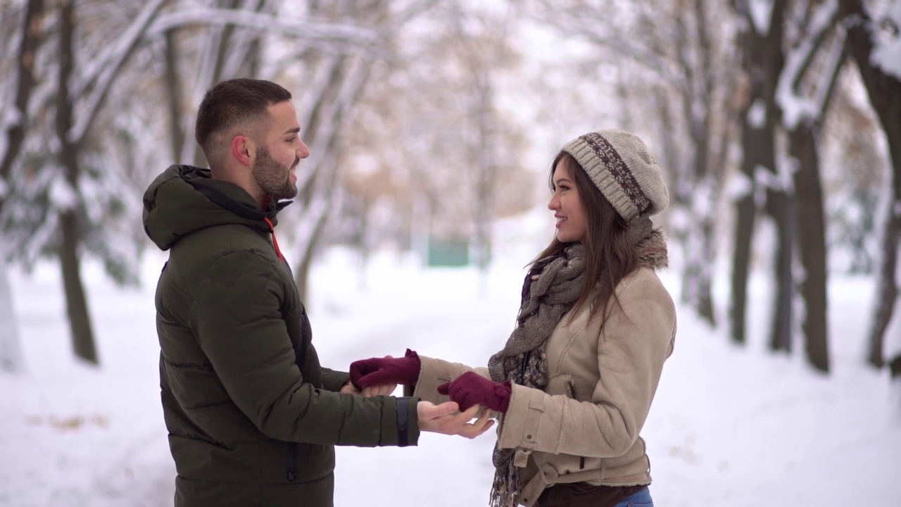 一对年轻的情侣在下雪的公园里接吻视频下载