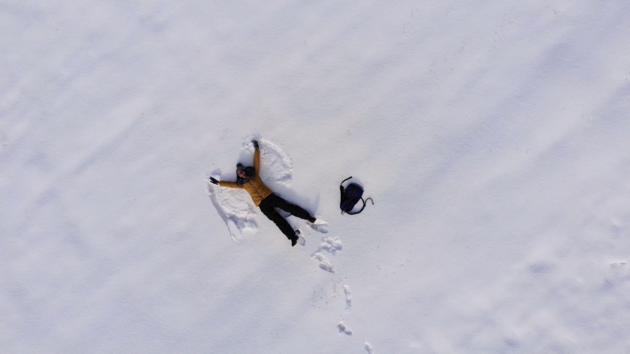 无人机拍到一个快乐的女人在做雪天使视频素材