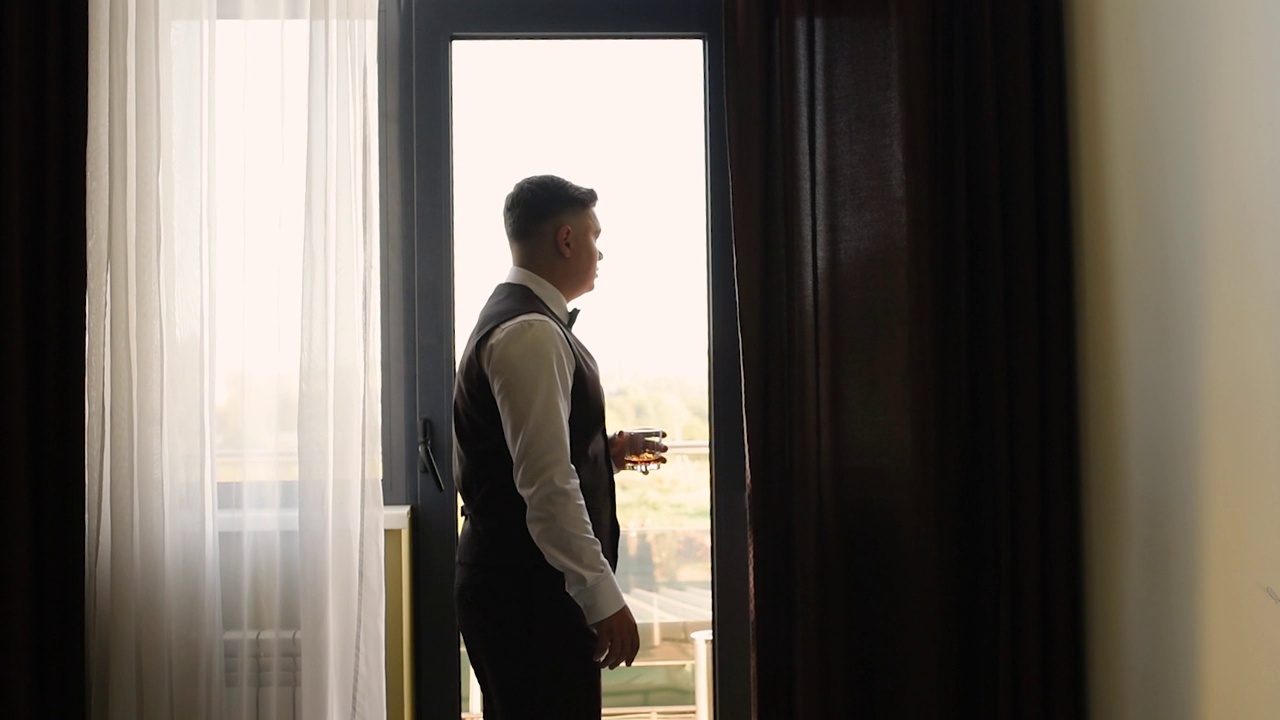 男子新郎商人成功站在公寓全景窗口拿着玻璃杯威士忌视频下载