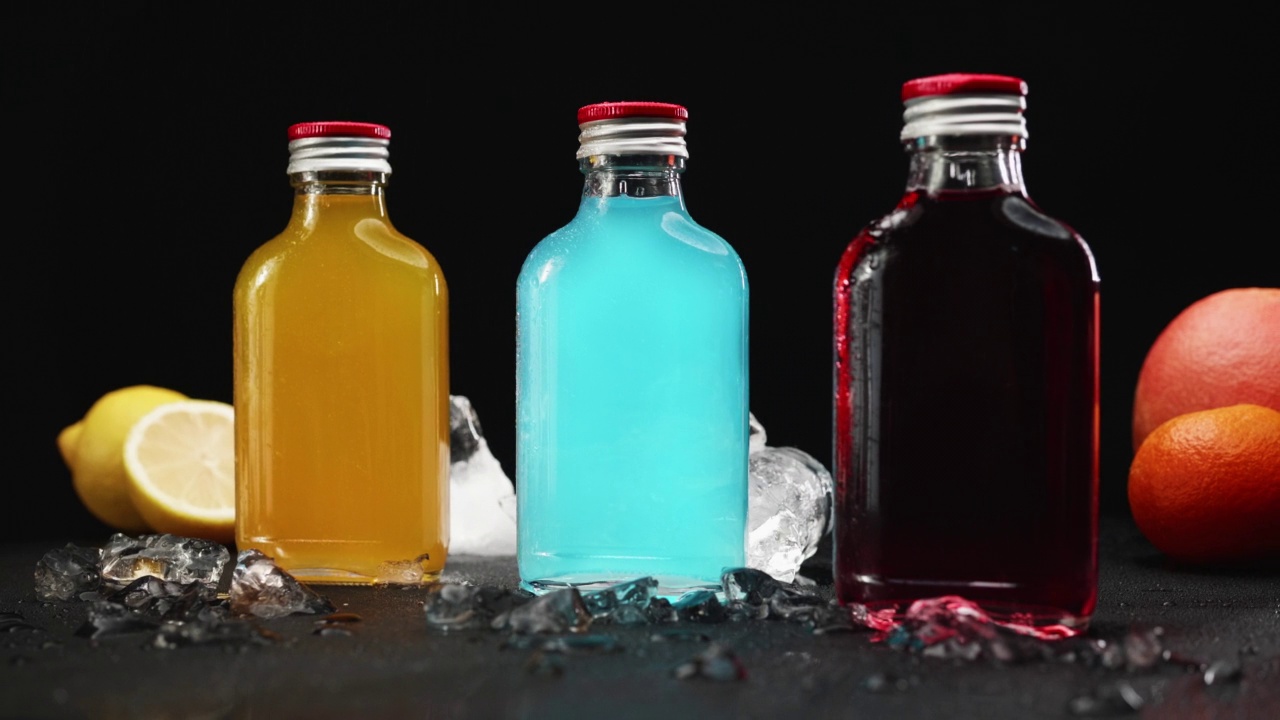 五颜六色的饮料装在旋转的玻璃瓶里，溅起了水视频下载