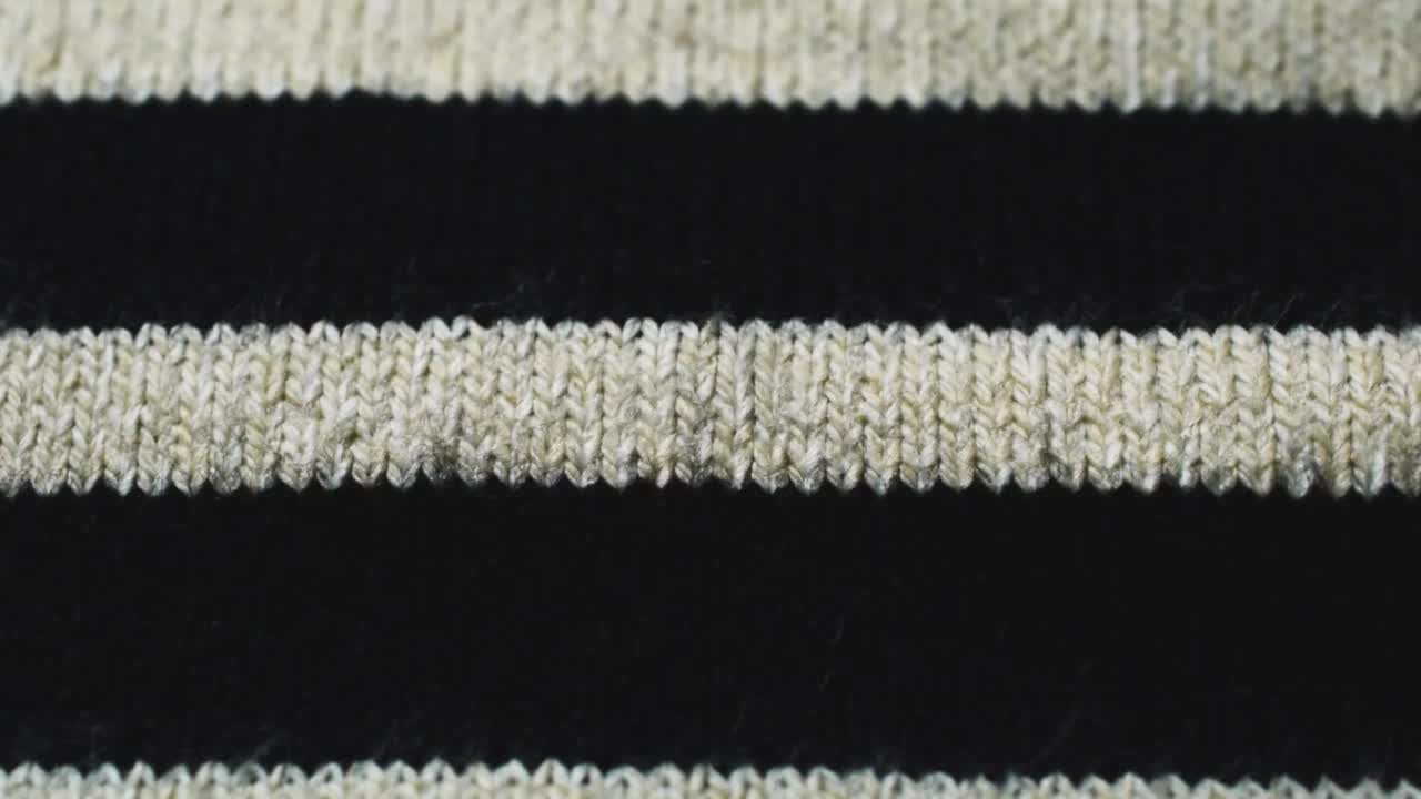 米色针织面料上的黑色线条。特写详细的毛衣织物背景。柔软的羊毛纺织图案为冬季时尚背景视频下载