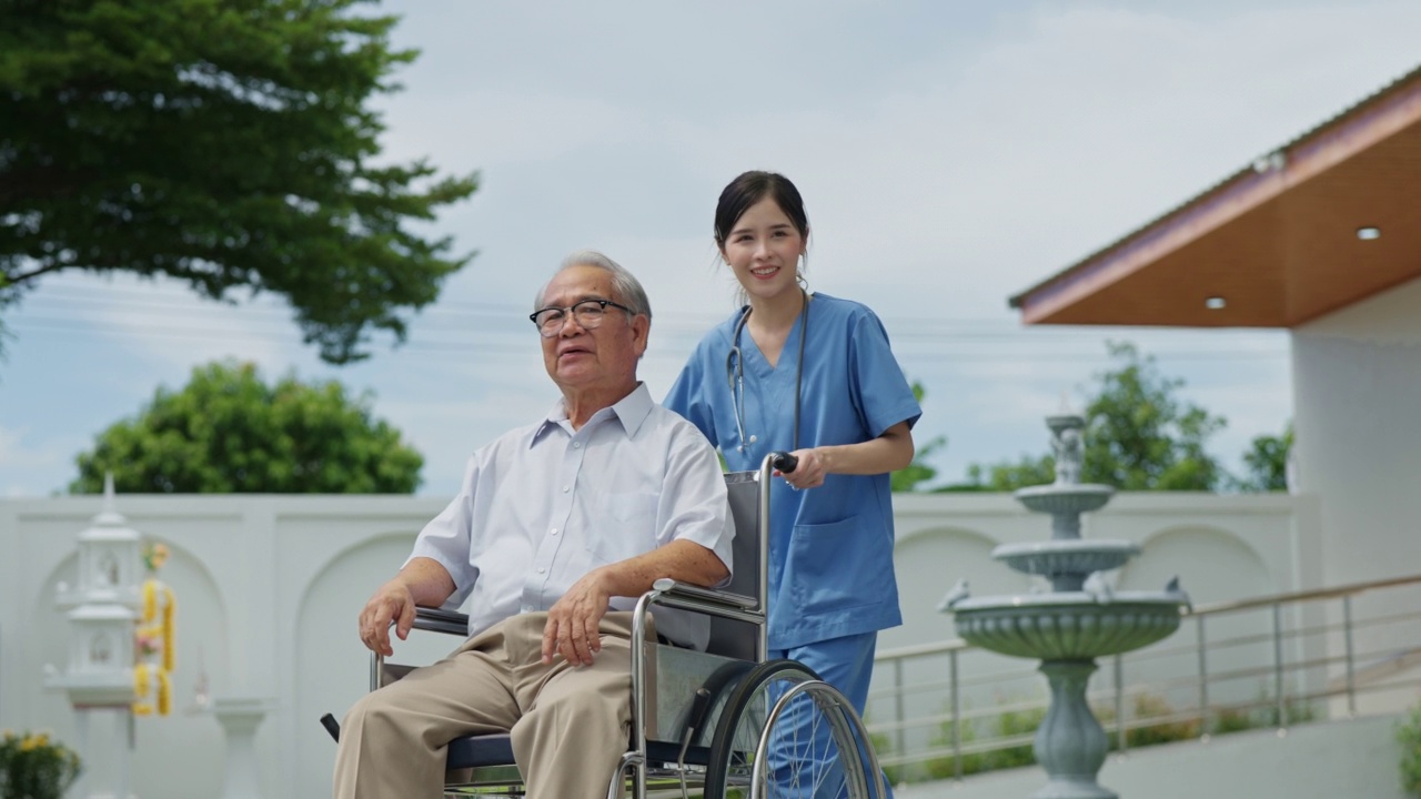 年轻的亚洲护理医生推着轮椅上的老人在养老院的花园里休息。精神保健和健康。护士照顾老人和理疗视频素材