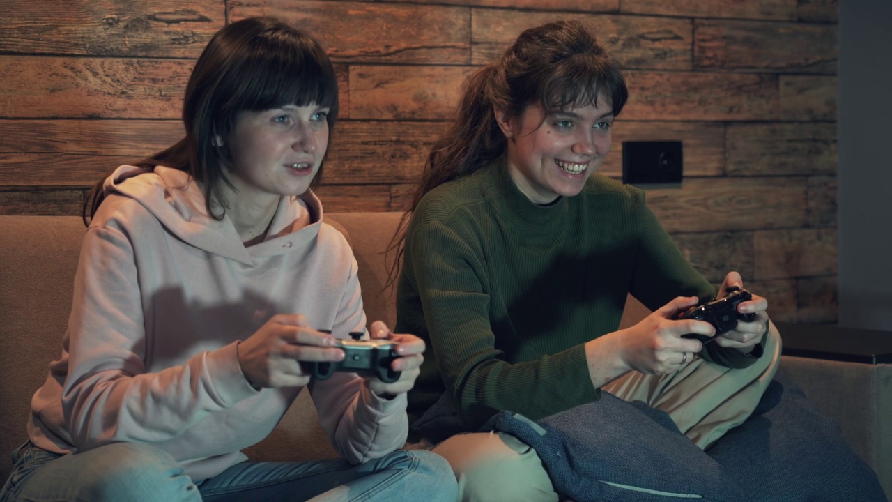 两个年轻的女性朋友晚上在家里玩电子游戏视频素材