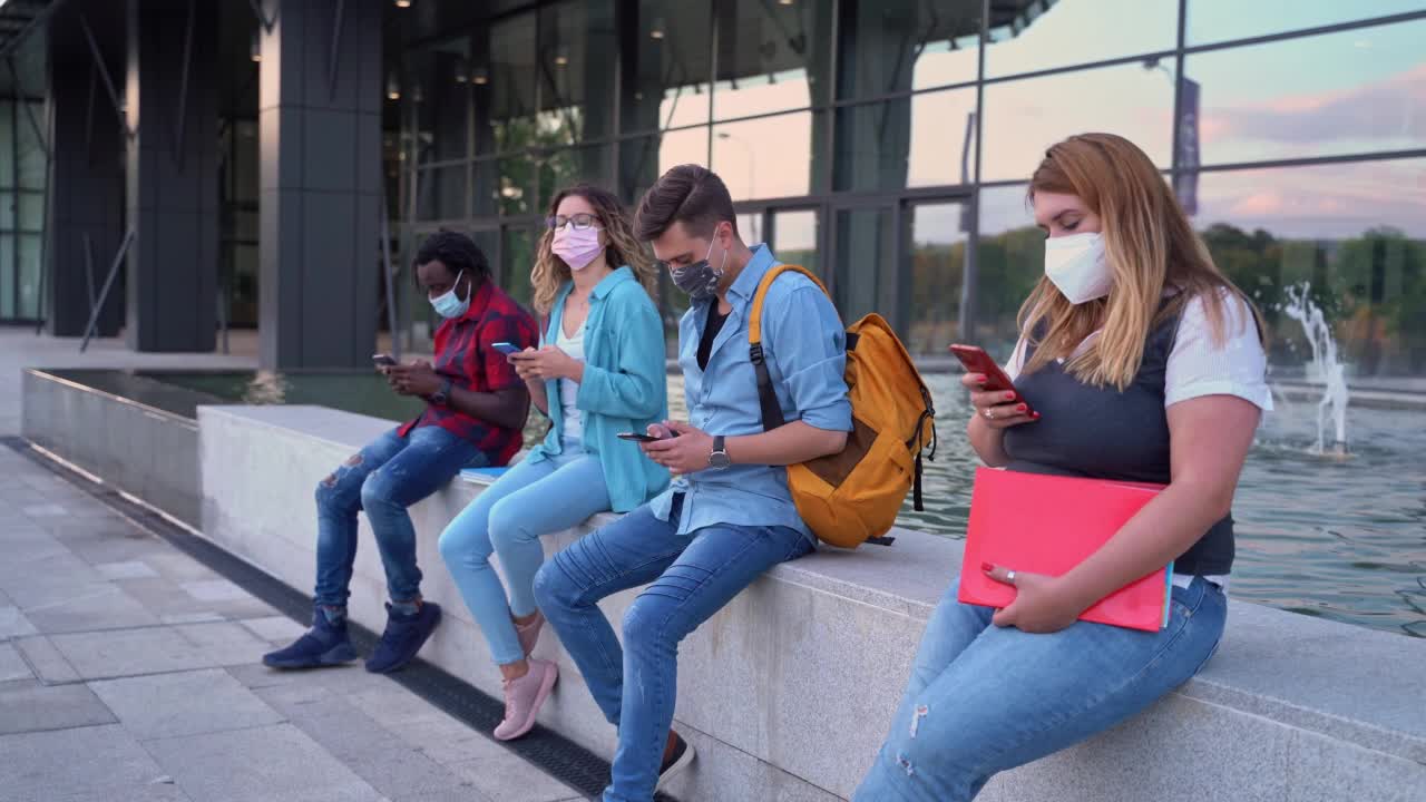 戴着口罩使用智能手机的学生视频素材