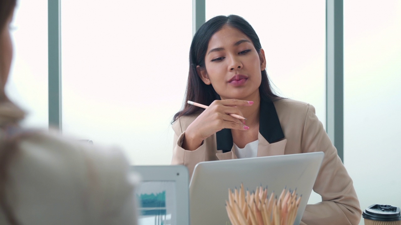 一位年轻的亚洲女商人正在会议室里听她的同事们集思广益。视频素材