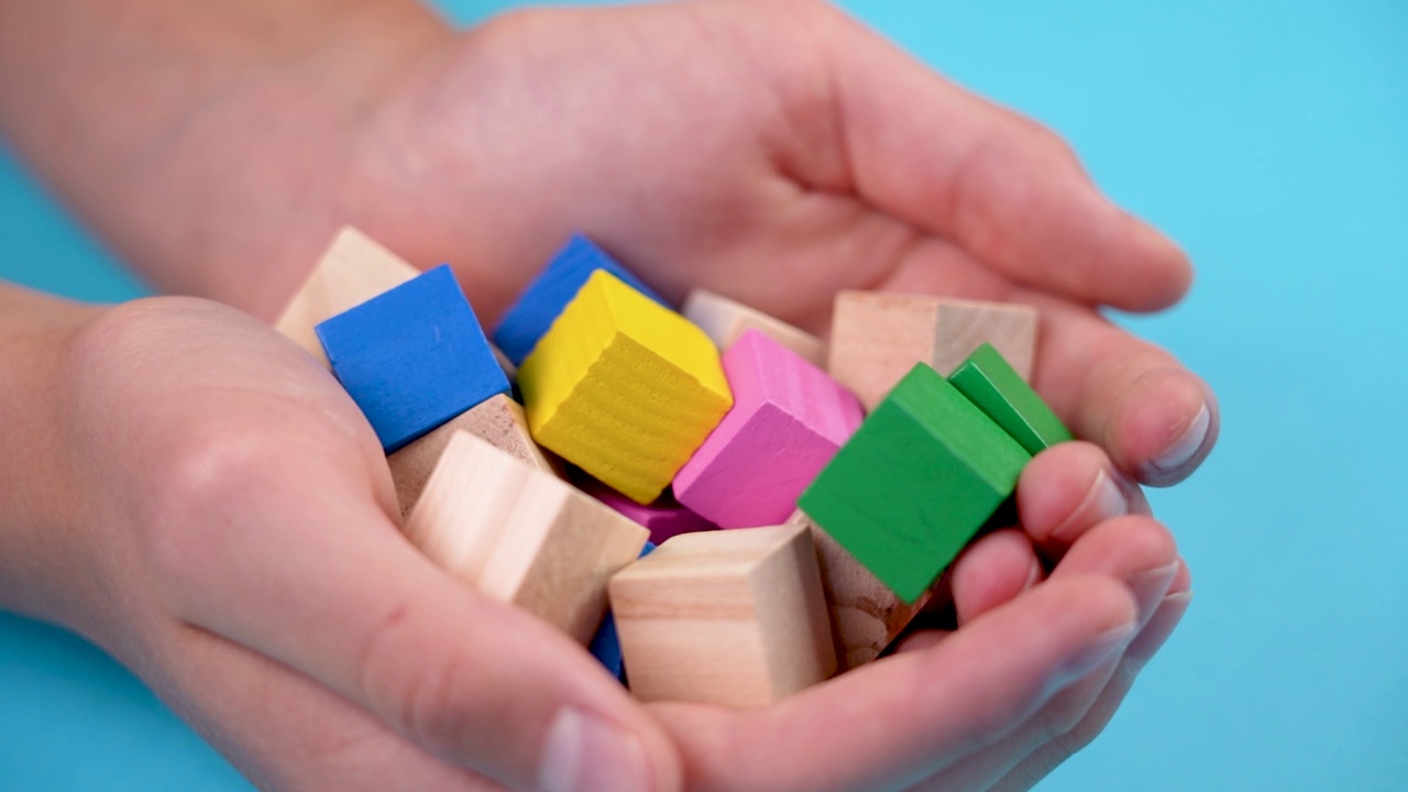 手里拿着五颜六色的木制玩具方块。明亮的游戏色块视频素材