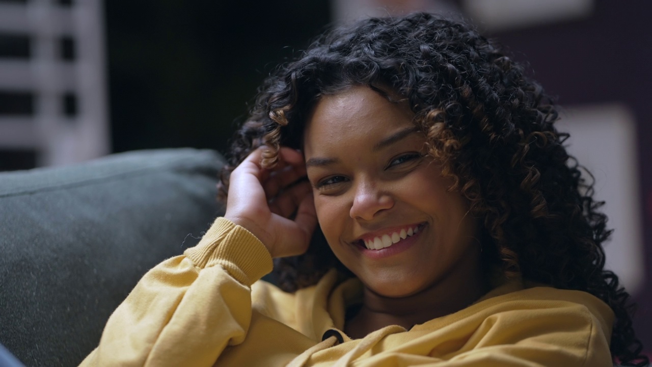 一个年轻的黑人妇女的肖像面对镜头微笑。快乐的非洲裔美国巴西女孩卷发视频素材