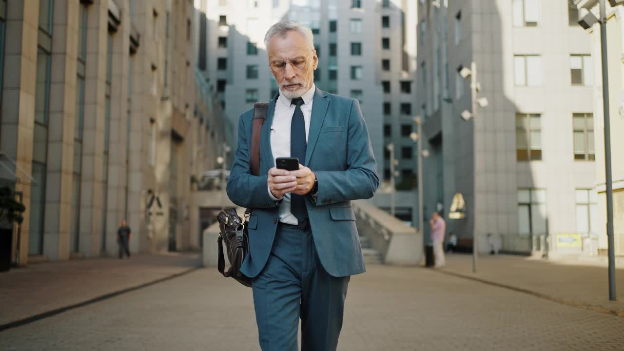 忙碌的老人在街上用智能手机解决工作问题视频素材