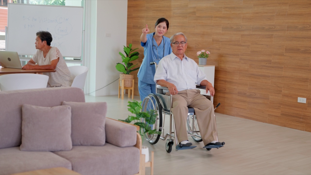 护士在家照顾坐在轮椅上的成年男性患者，快乐的老年患者在轮椅上度过退休后的时光。视频下载