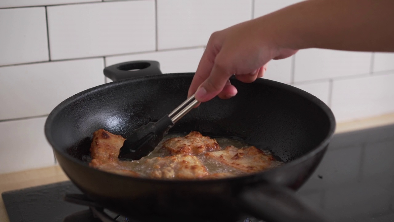 在自家厨房用油锅煎香脆的五花肉。不健康的亚洲食物高胆固醇的肉类准备晚餐视频素材