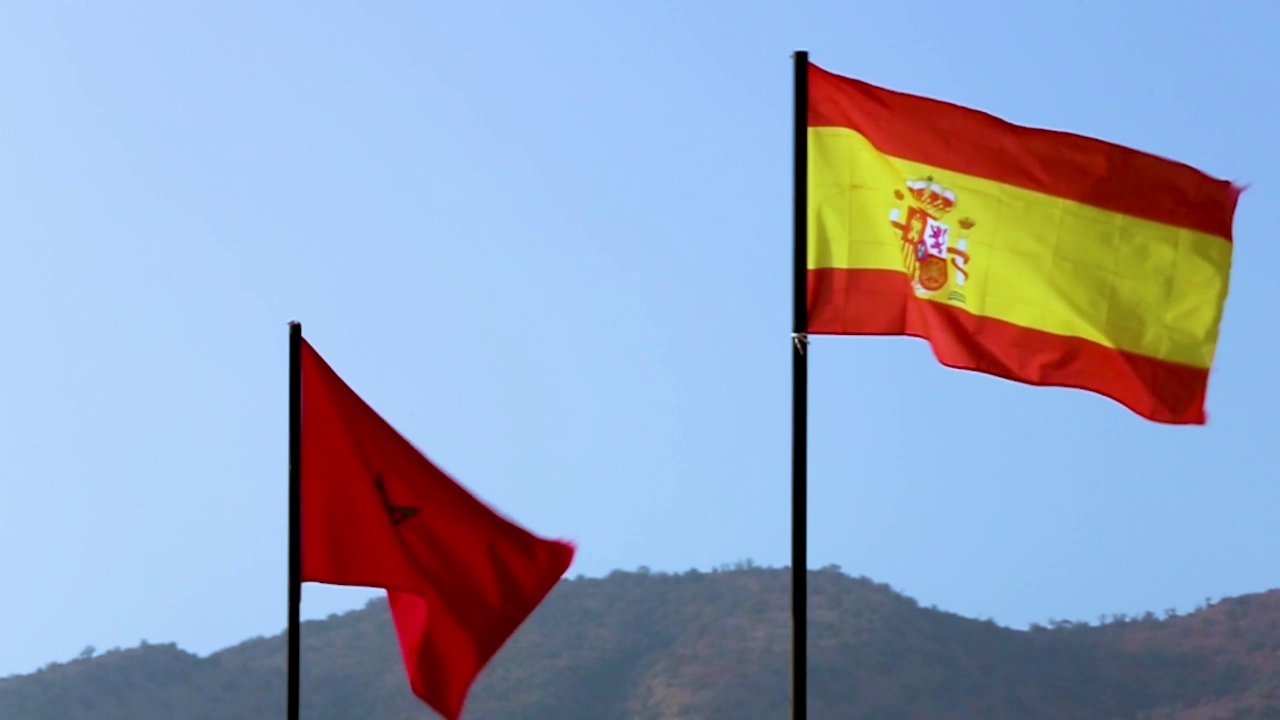 摩洛哥和西班牙的国旗在蓝天中缓缓飘扬视频素材