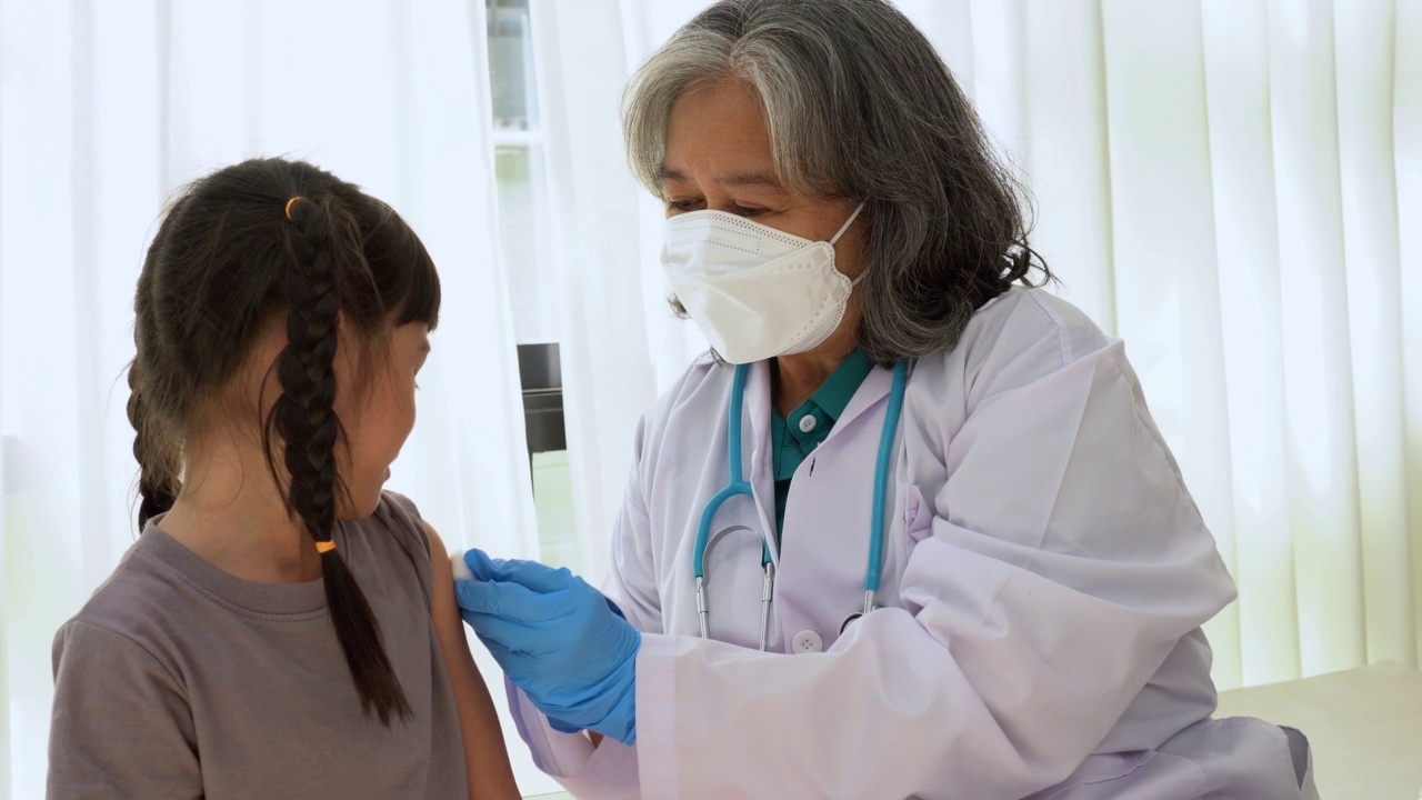 医生拿着注射器，准备在医院的亚洲女孩的肩膀上接种疫苗。儿科医生为孩子们接种疫苗。种痘、免疫、防病观念。视频素材
