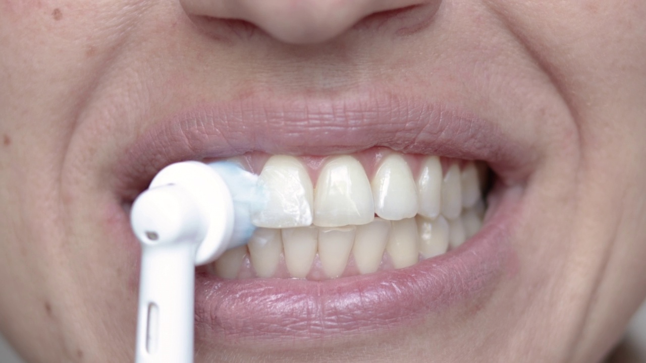 女士用电动牙刷清洁牙齿，靠近口腔视频素材