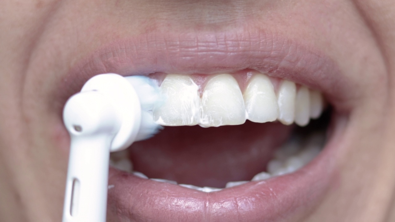女士用电动牙刷清洁牙齿，靠近口腔视频素材