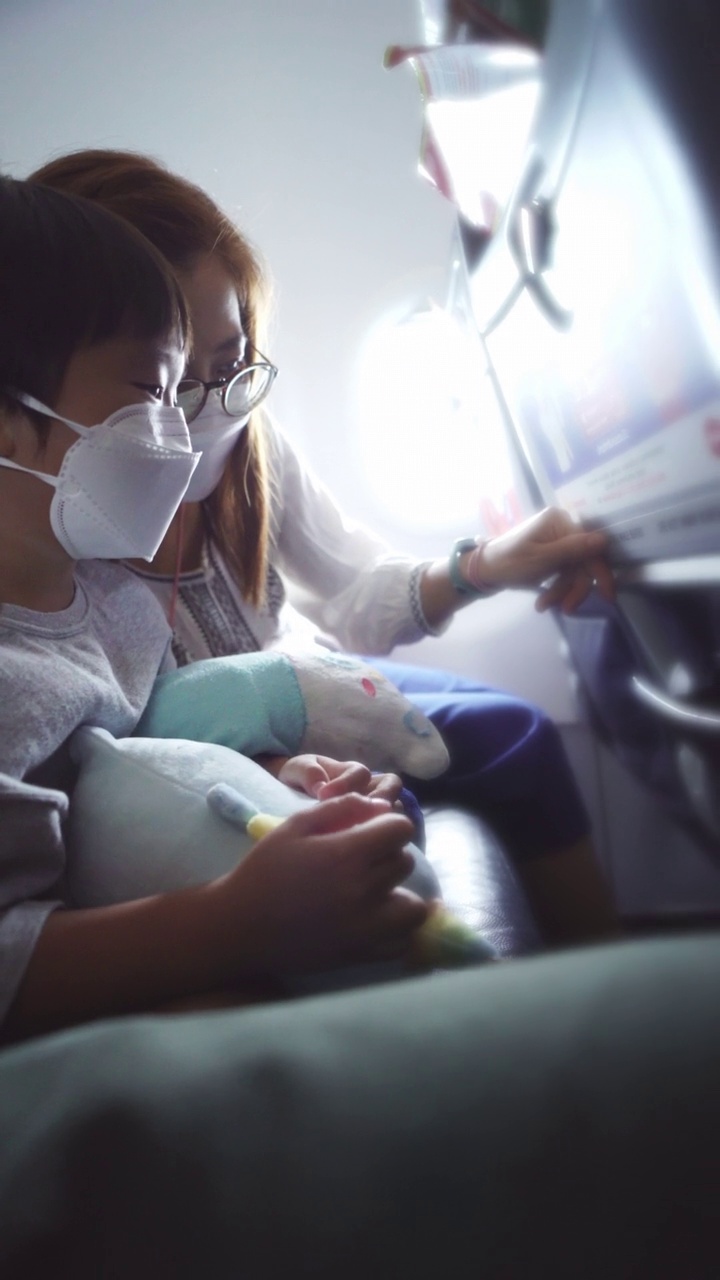 第一次飞行，小男孩抱着娃娃坐在飞机的座位上视频素材