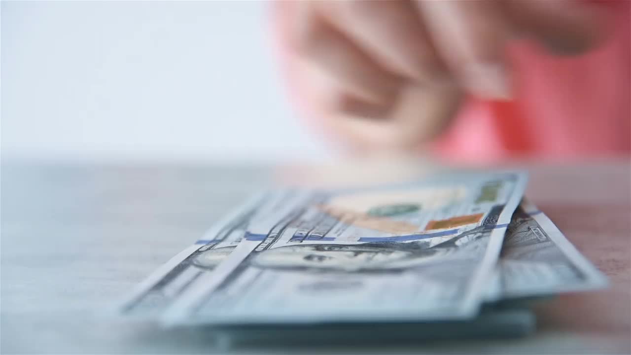 一名妇女在办公室用手数美元钞票。视频下载