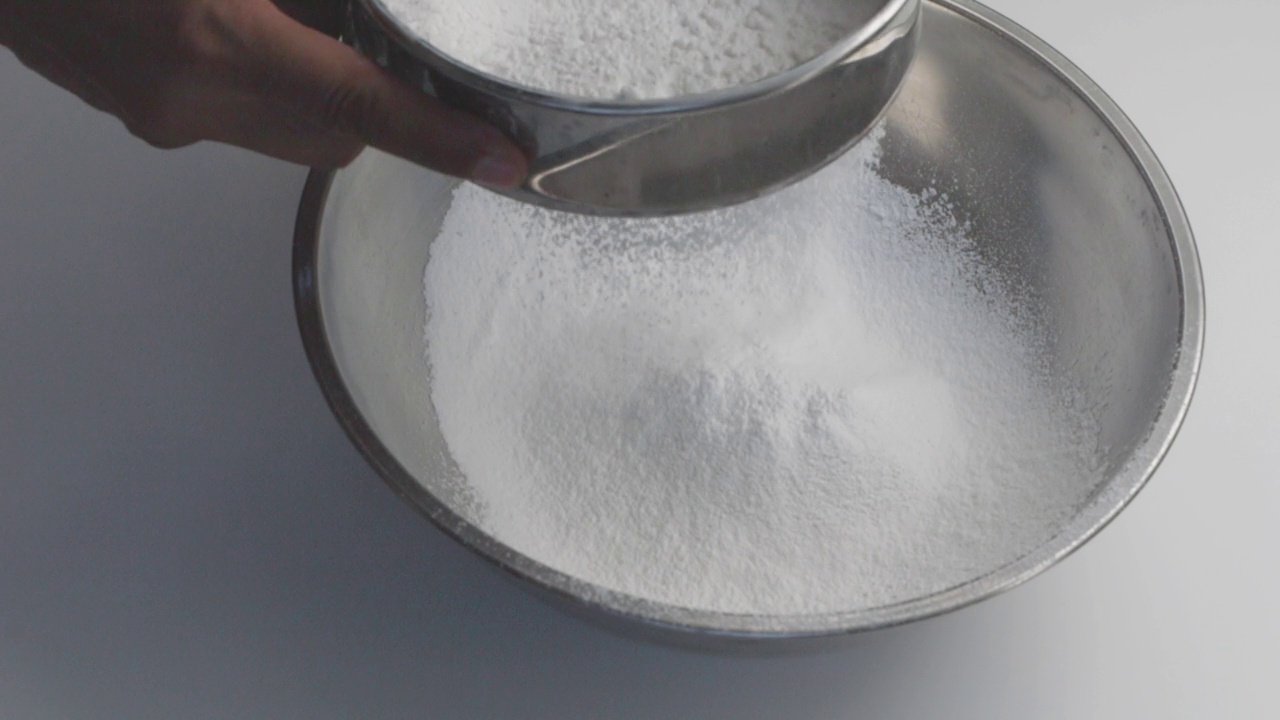 厨房里的面粉筛中落下的白色细面粉的特写镜头。,慢动作视频素材