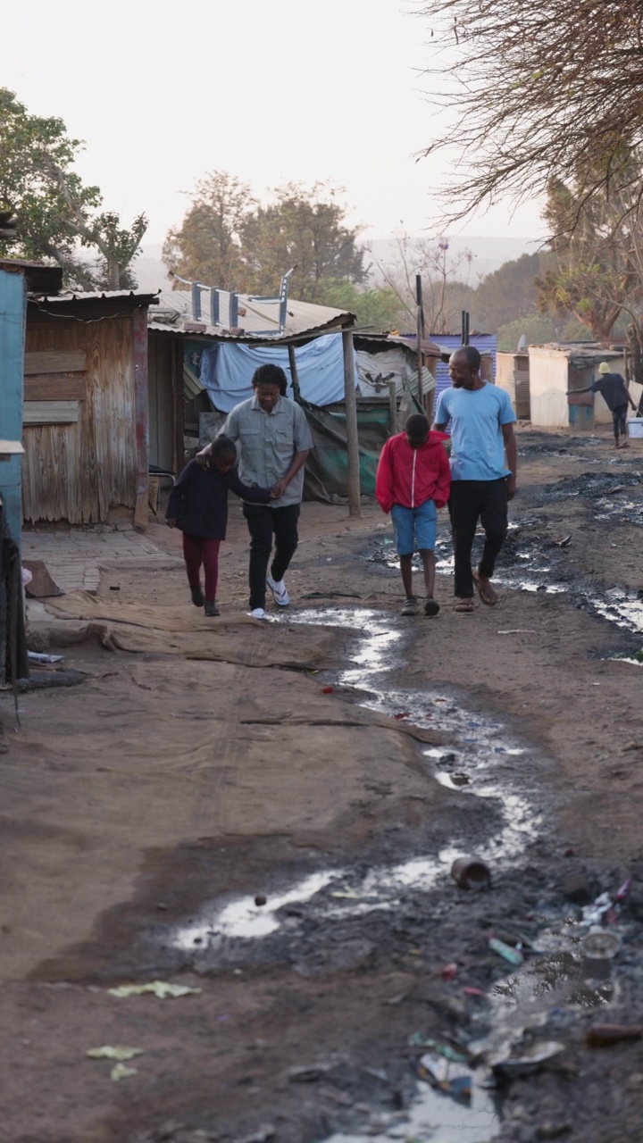 垂直video.Poverty。不平等。贫穷的非洲黑人家庭走在一个典型的贫民窟，展示了非洲贫困的环境和水的浪费视频素材