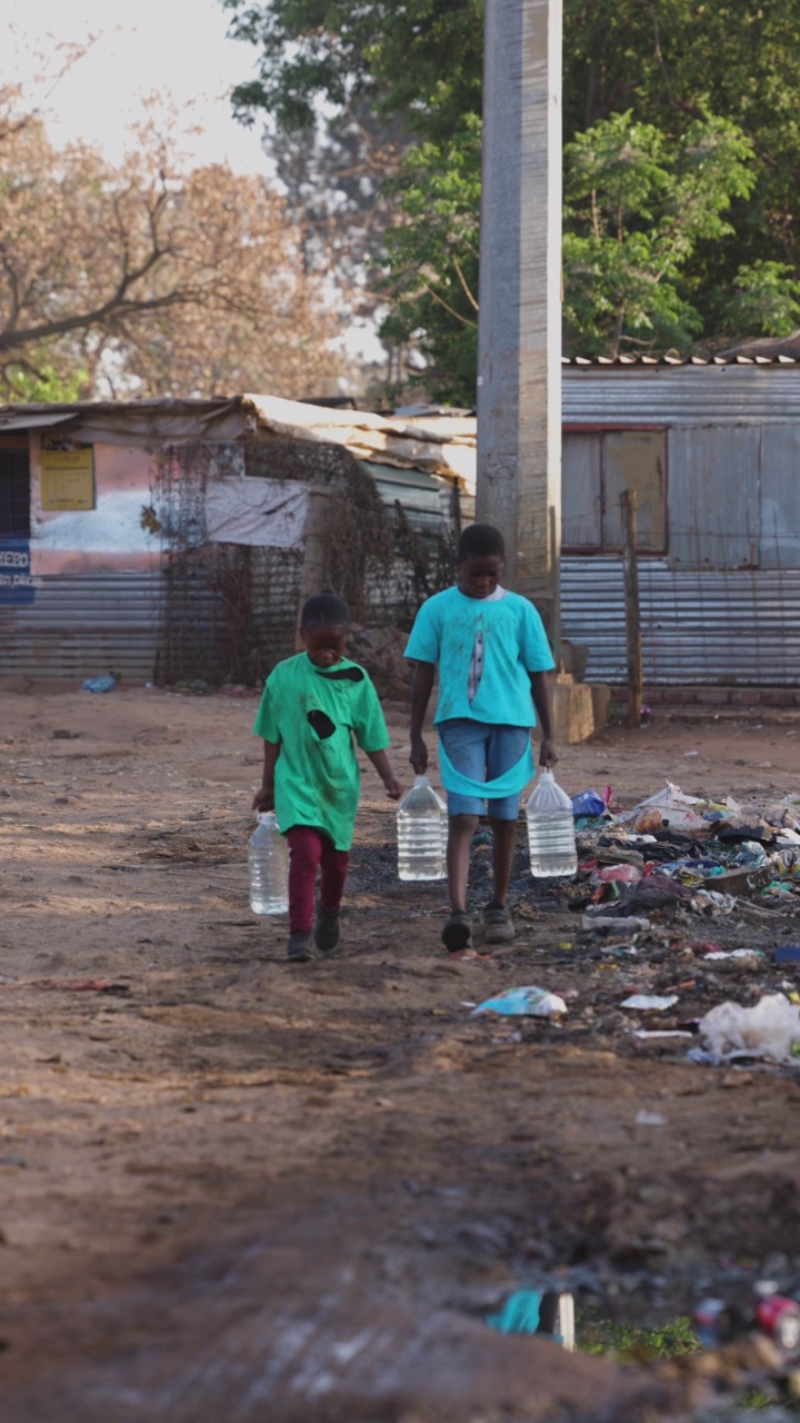 Poverty.Inequality。气候变化。两个年轻的非洲黑人儿童为家庭取水的特写。生活条件差，没有干净的自来水。视频素材