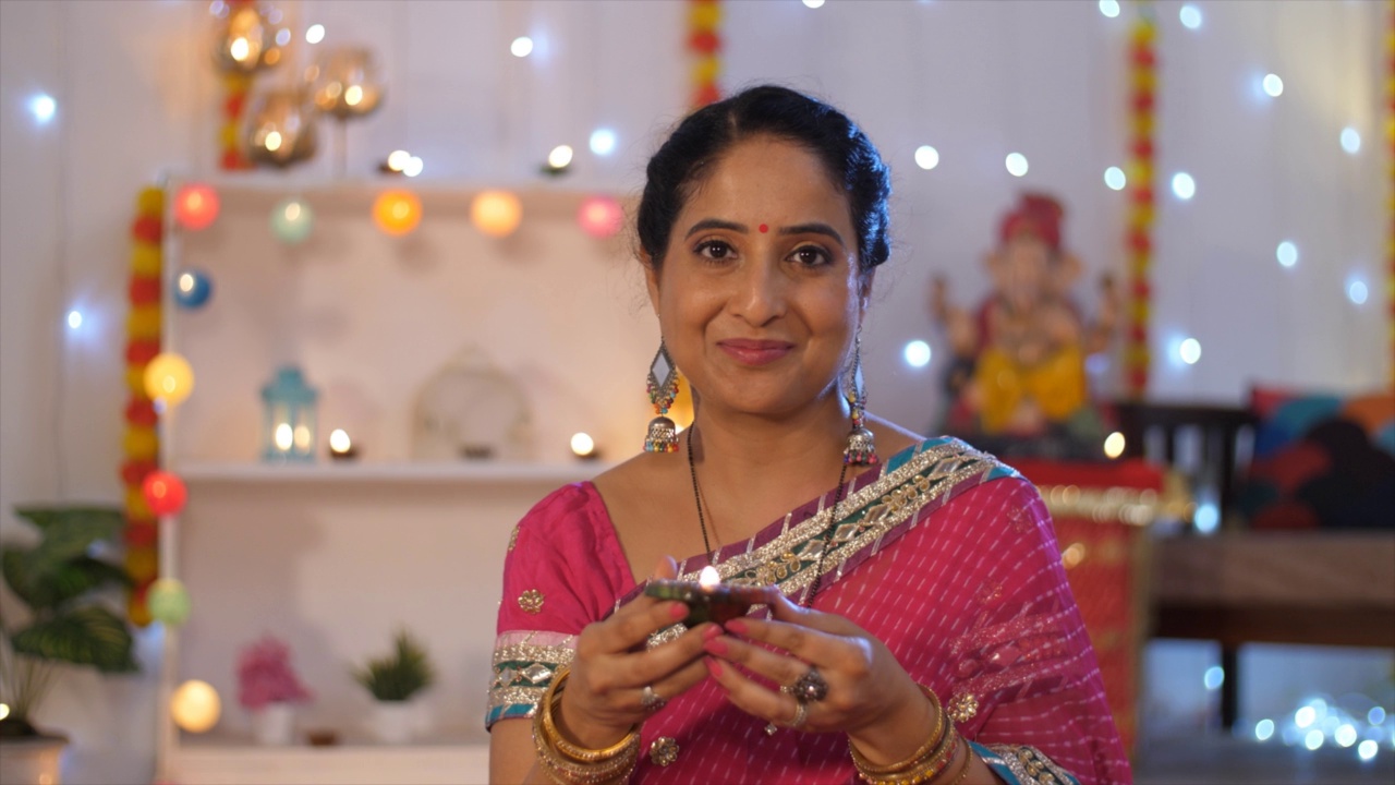 一名美丽的印度妇女穿着五颜六色的纱丽手持Diya -节日季节，排灯节庆祝活动视频素材