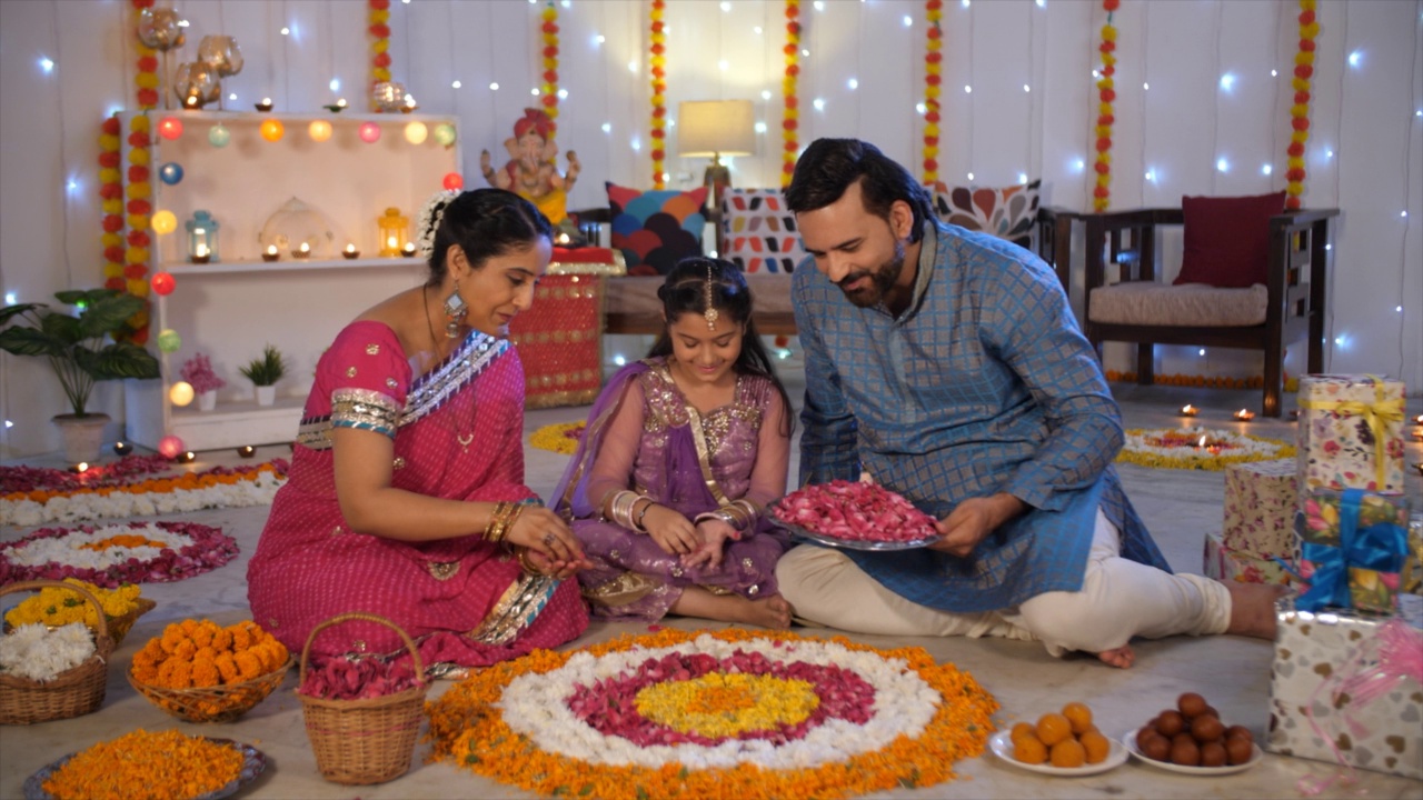 一对中年印度夫妇和他们的女儿正在用玫瑰花瓣装饰兰花——排灯节装饰视频素材