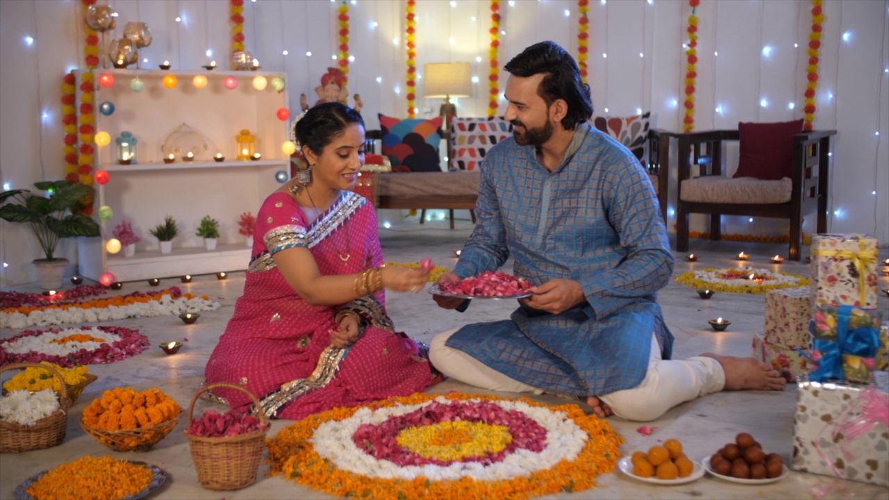 一对中年印度夫妇正在用玫瑰花瓣装饰排灯节的兰花视频素材