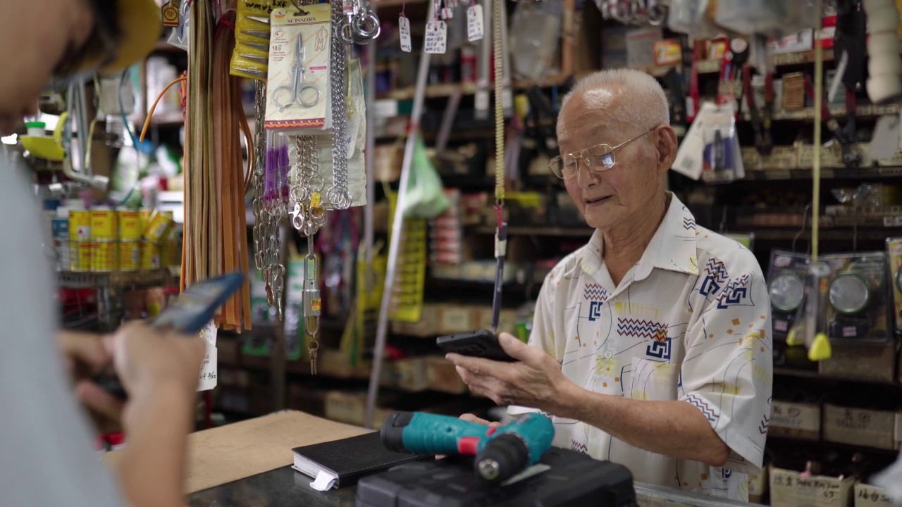 亚裔华人员工在五金零售店使用移动电子钱包付款视频素材
