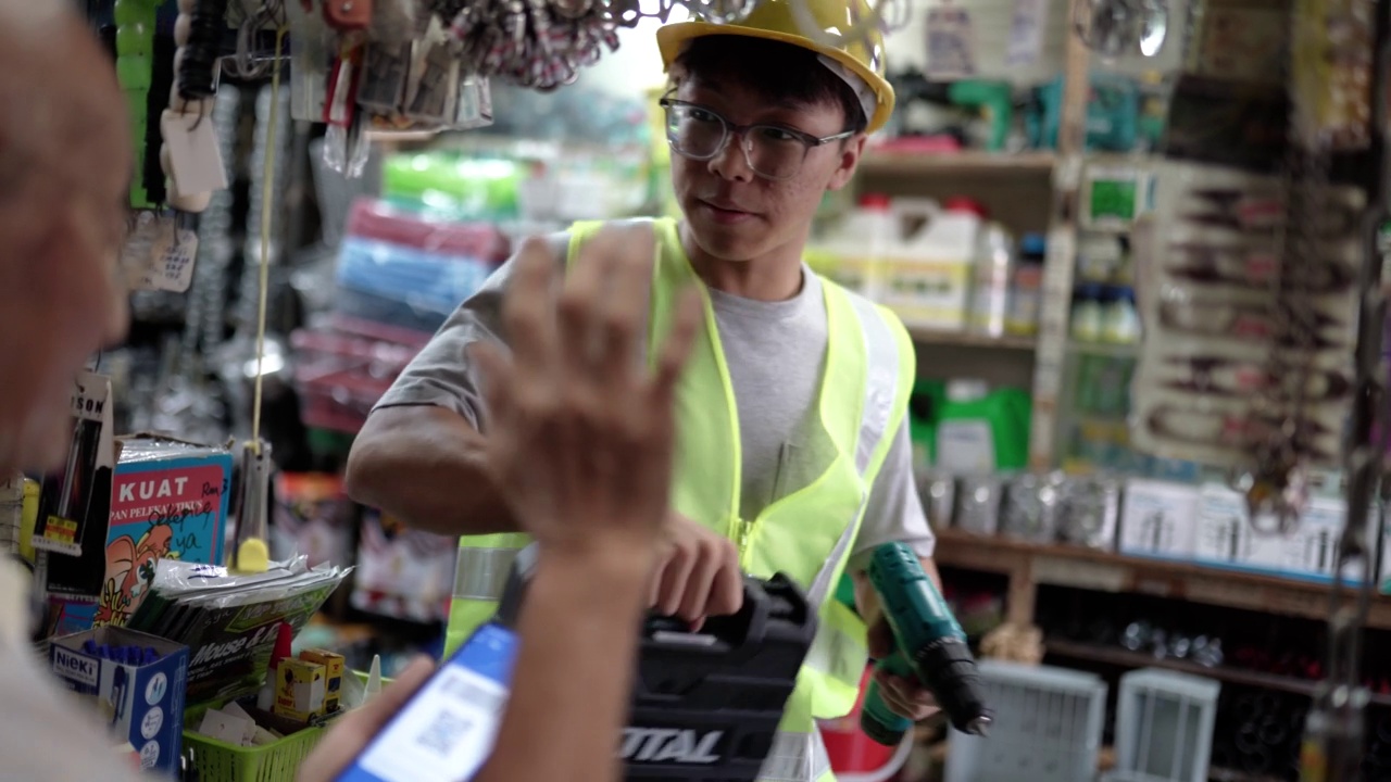 亚裔华人员工在五金零售店使用移动电子钱包付款视频素材