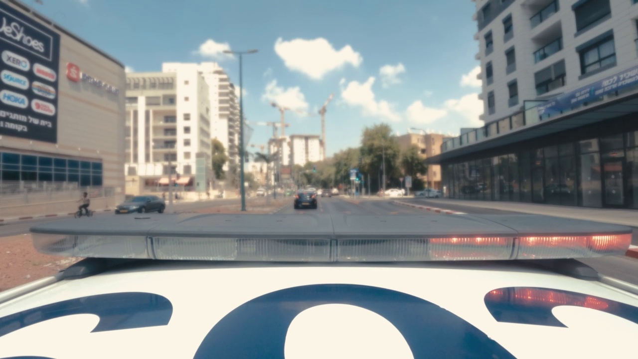 一辆带着蓝色和红色灯的警车在城市街道上快速行驶视频素材