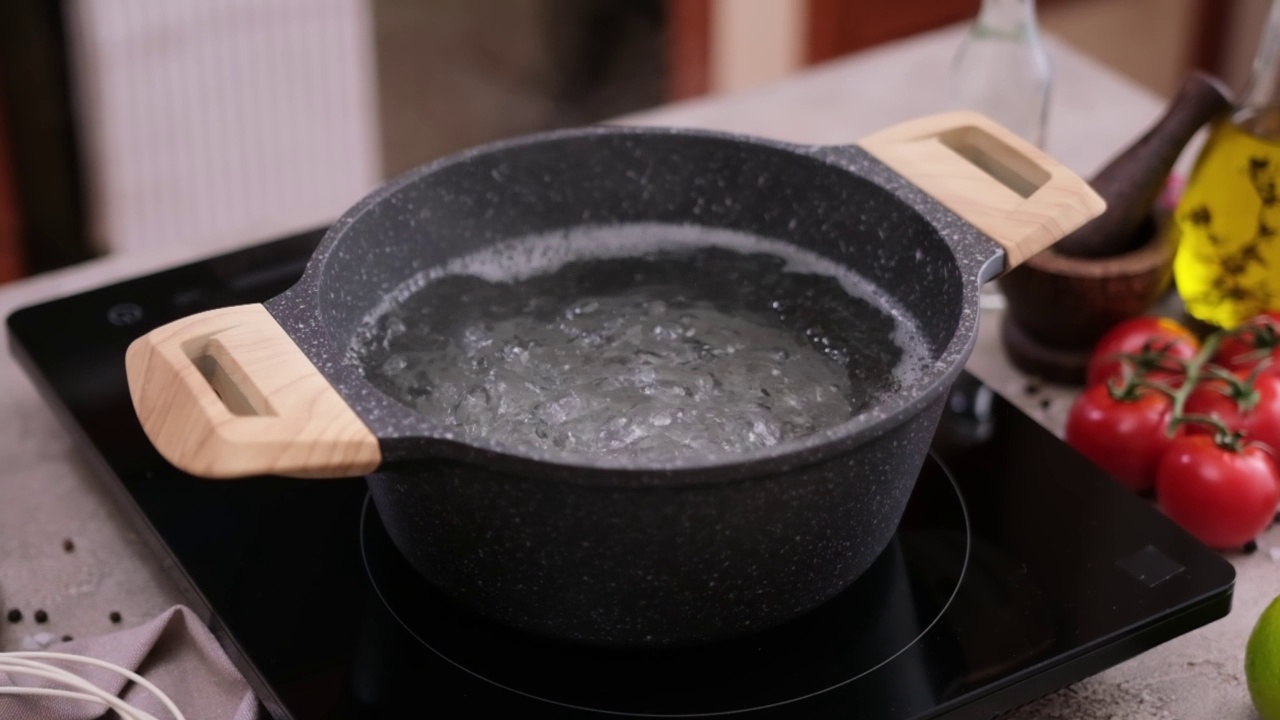 家庭厨房电磁炉上的锅里烧开的水视频下载