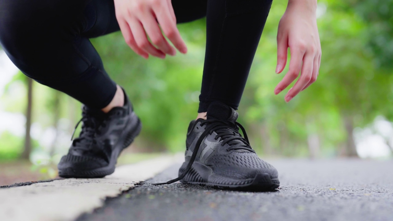 特写的女人系鞋带。亚洲女性运动健身运动员准备在公园户外慢跑视频下载