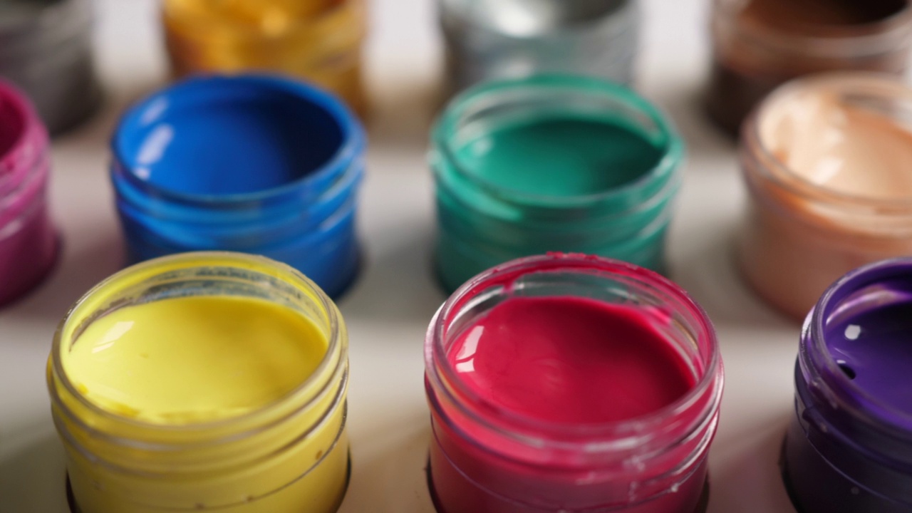 设置水粉颜料在罐中明亮的颜色接近。一套彩色水粉塑料瓶。多利拍摄了多色背景。背景多色油漆。创意绘画艺术爱好。视频素材