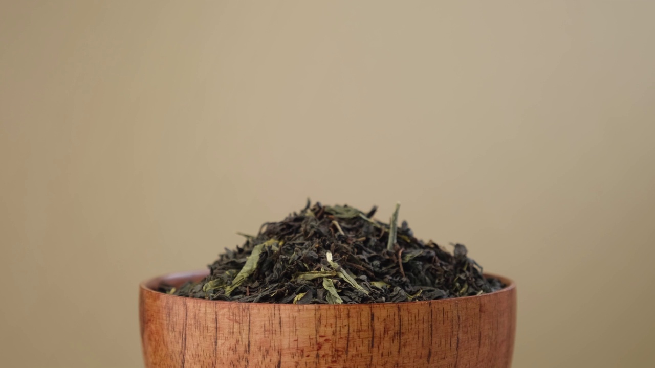 黑干茶倒在碗里。一堆混合红茶和绿茶的叶子。近,宏。前视图。纹理。副本的空间。干茶在转盘上旋转。饮食背景视频下载
