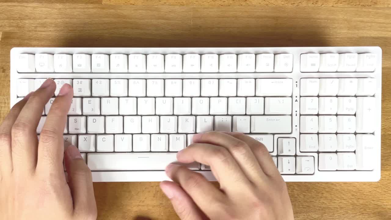 男人的手在白色的键盘上打字，在一张木桌上工作视频素材