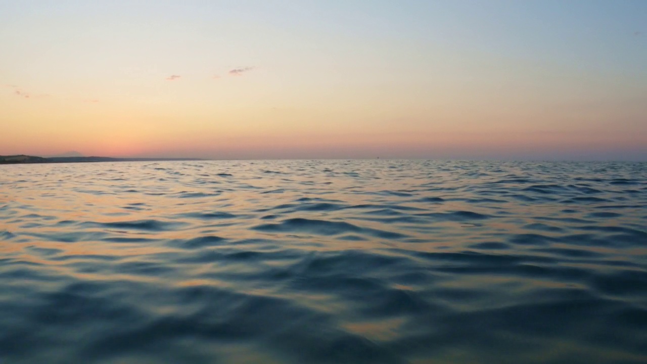 日落时在海水表面移动的低角度pov。第一人称视角视频素材