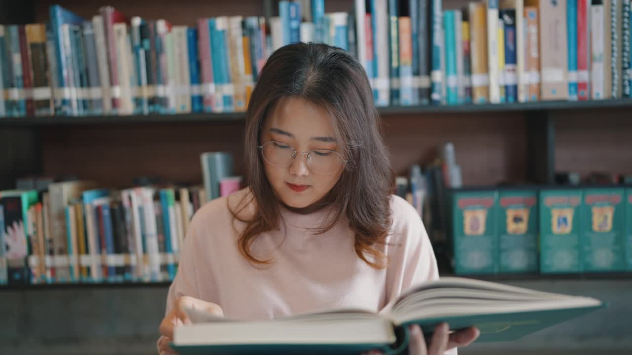 戴眼镜的亚洲女学生为课堂作业读书视频素材