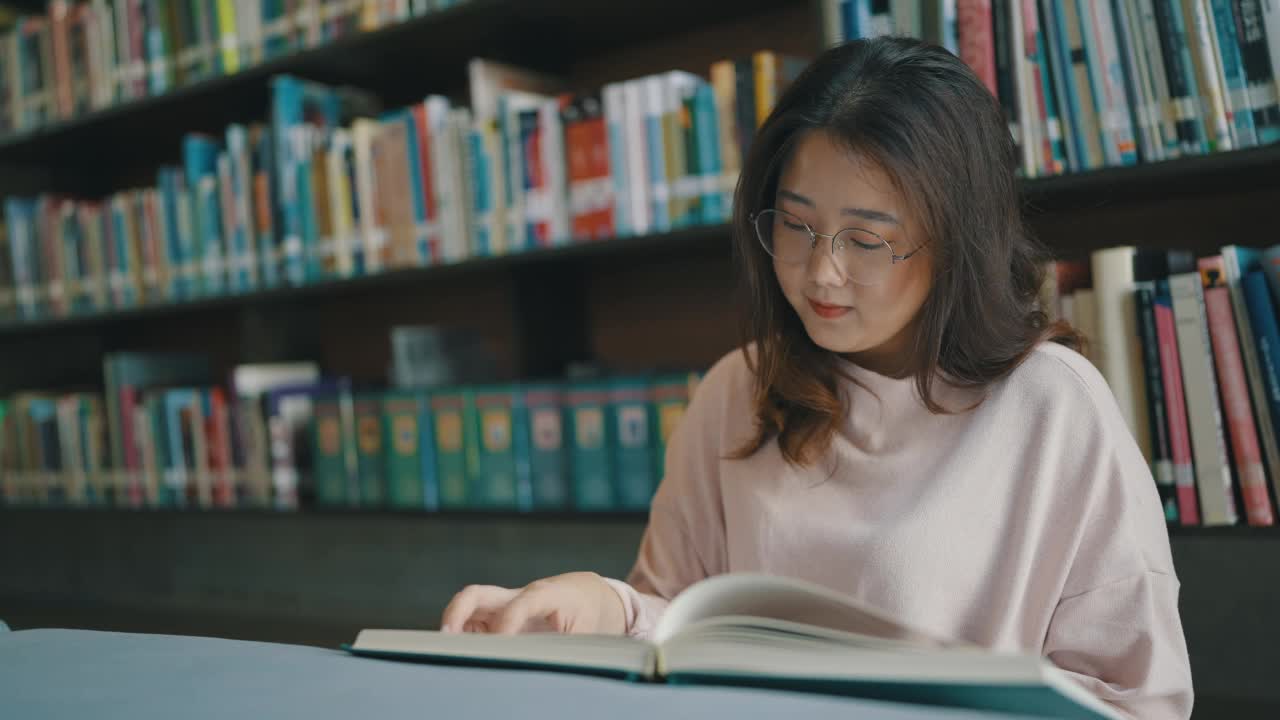 戴眼镜的亚洲女学生为课堂作业读书视频下载