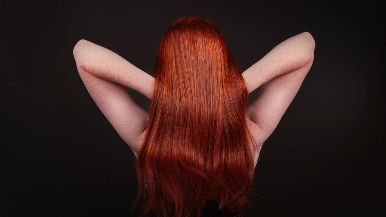 迷人的红发女子翻转她的长直发。后视视频下载